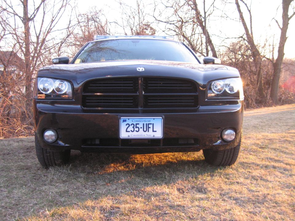 Front view of black Dodge Charger with roof light bar and Connecticut plate