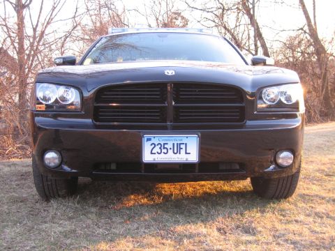 1991 Ford LTD Crown Victoria - Head-on front view of a black Dodge Charger with a roof light bar and a Connecticut plate reading 235 UFL, parked in a grassy field.