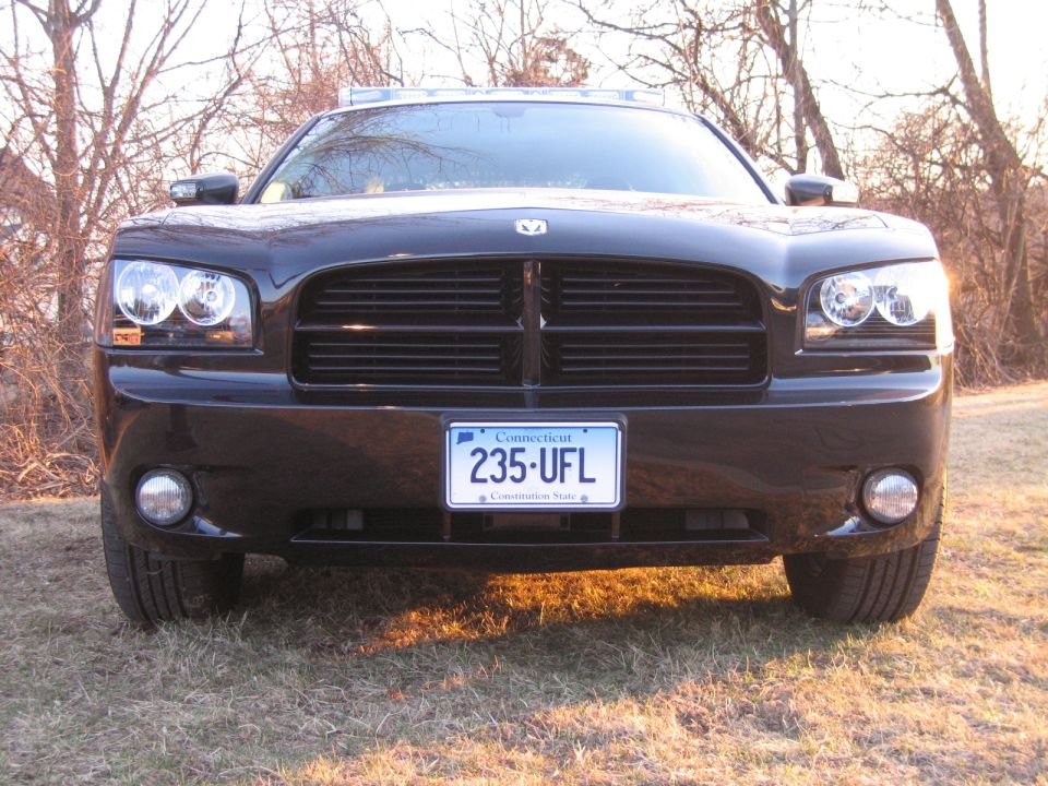 Front view of black Dodge Charger with roof light bar in grassy field