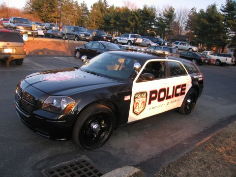 1991 Ford LTD Crown Victoria - Front three-quarter view of a black-and-white Dodge Magnum police wagon marked POLICE Protect & Serve with a ram-crest badge.