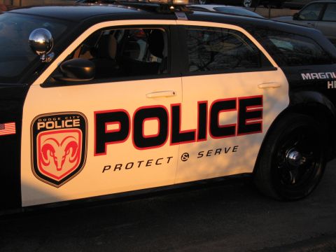 1991 Ford LTD Crown Victoria - Close-up of a white police car door showing a ram-crest Dodge City Police badge and bold POLICE Protect & Serve lettering.