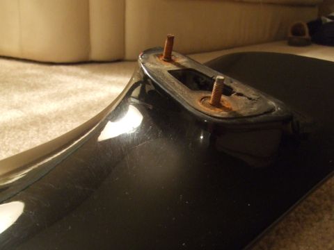 1995 Ford Probe - This black car part shows signs of wear with two rusty bolts protruding from its mounting point.