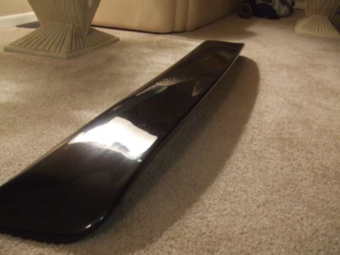 1995 Ford Probe - A black car spoiler lies on a carpeted floor, reflecting light.