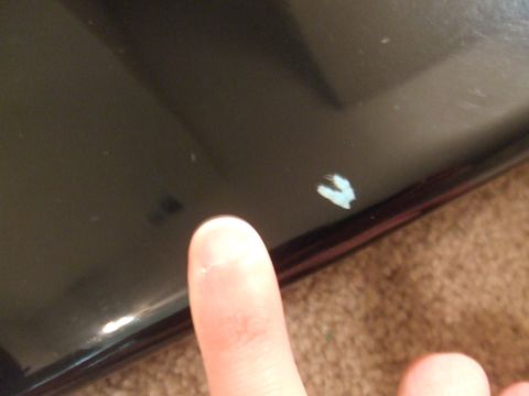 1995 Ford Probe - A finger points to a small chip on the dark exterior panel of a vehicle.