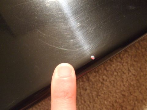 1995 Ford Probe - Close-up of a small chip on a dark surface, with a finger indicating the damage.