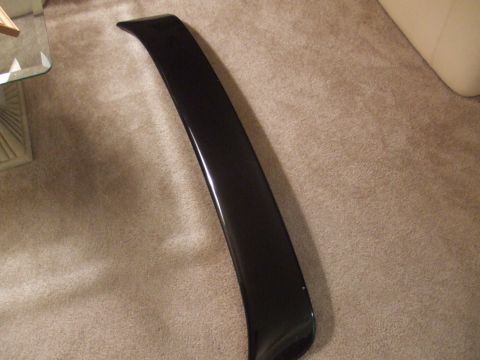 1995 Ford Probe - A black car spoiler is shown resting on a carpeted floor next to a glass table.