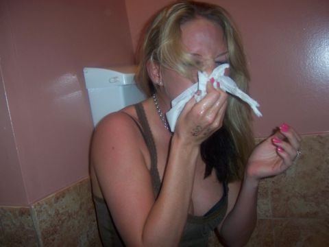1989 Ford Bronco - A woman is sitting on a toilet and blowing her nose with a tissue.