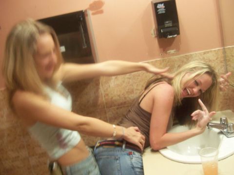 1989 Ford Bronco - Two women are playfully interacting in a bathroom setting, with a soap dispenser visible on the wall.