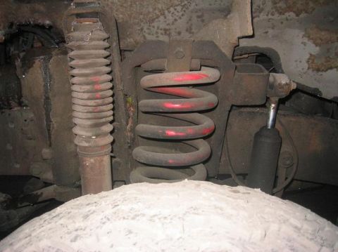 1986 Ford Bronco - Close-up of a vehicle's front axle suspension system, showing a coil spring and shock absorber.