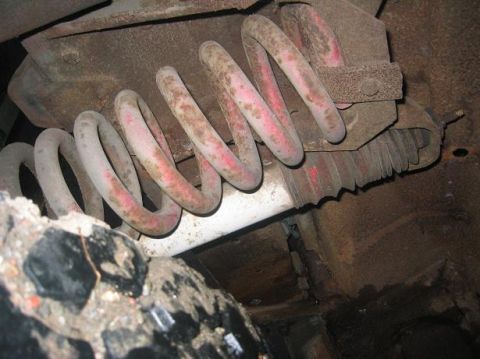 1986 Ford Bronco - Close-up view of a front axle suspension spring, showing red paint markings and signs of wear.