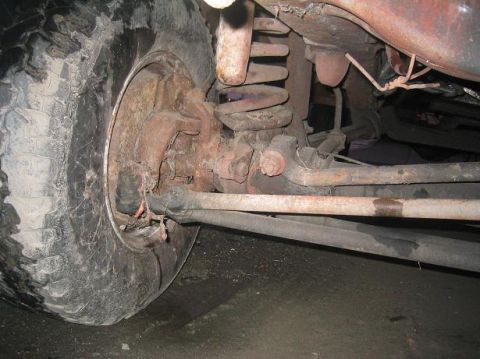1986 Ford Bronco - The photo shows the front wheel, brake assembly, and suspension of a vehicle, with visible rust and damage.