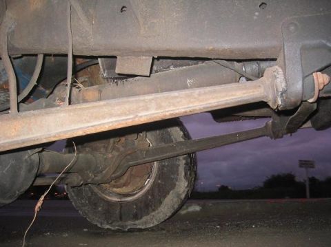 1986 Ford Bronco - This photo shows the undercarriage of a vehicle, focusing on the front axle and suspension system.