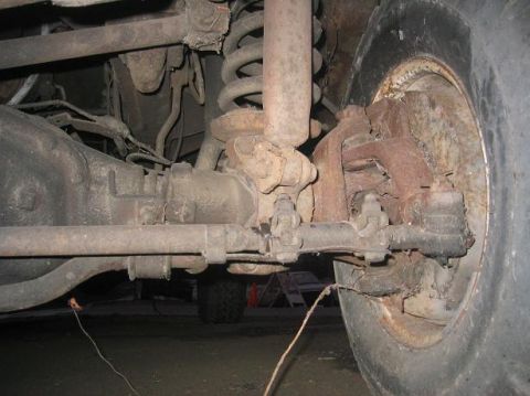 1986 Ford Bronco - Close-up view of a heavily corroded front axle assembly, showing wear and tear on suspension components.