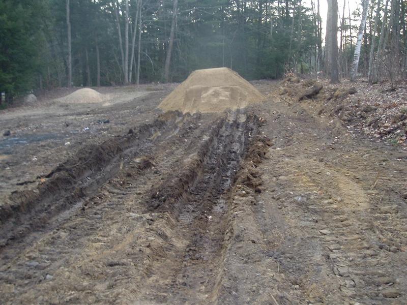 Dirt ramp with tire tracks in a wooded area