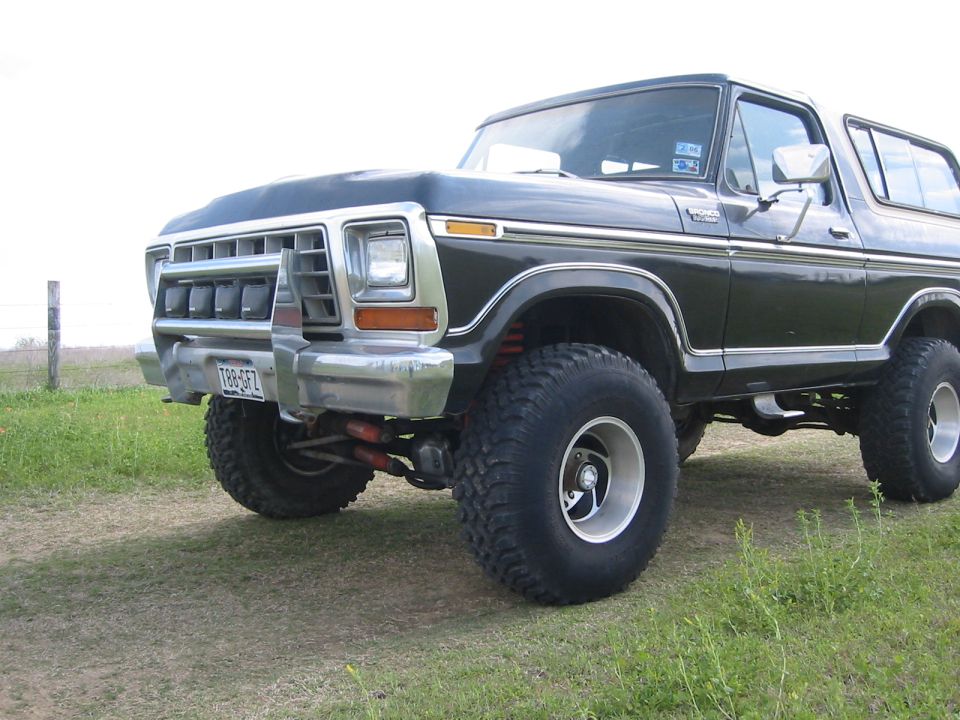 Front three-quarter of a lifted black Ford Bronco showing grille and mud tire