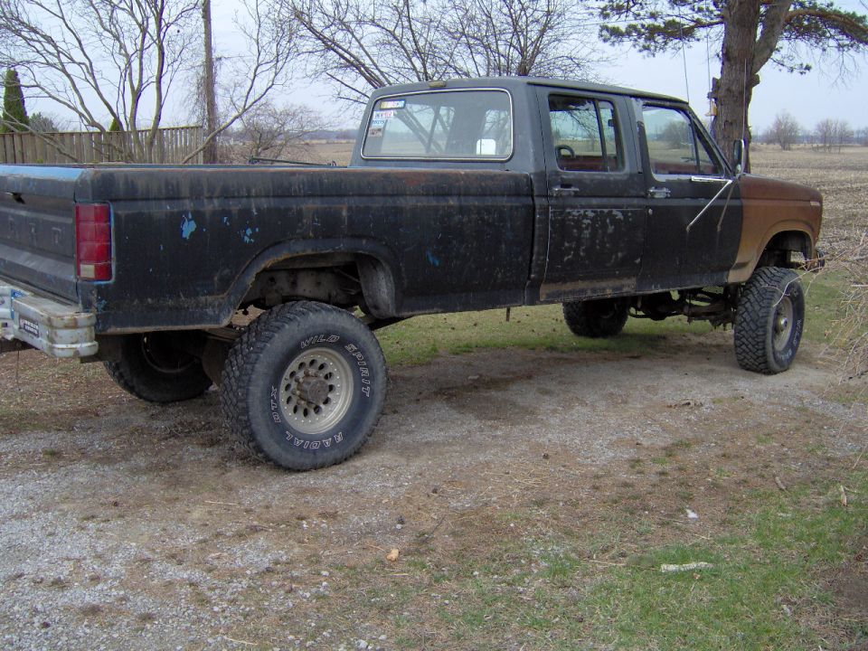 Black Ford F-350 crew cab pickup truck with lifted suspension and aftermarket wheels, parked outdoors
