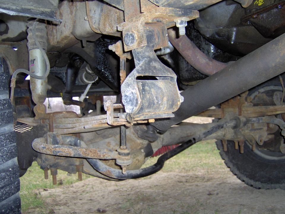 Undercarriage of a truck showing leaf springs, shock absorber, and exhaust pipe