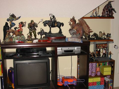 1991 Ford Bronco - A collection of fantasy and sci-fi figures displayed on shelves above a television and media console.