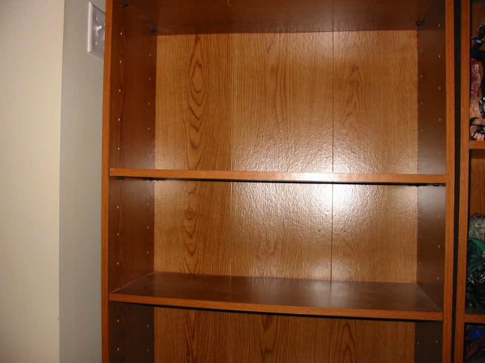 Empty wooden bookshelf with a light switch on the adjacent wall