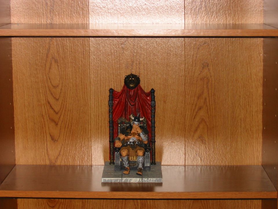 Toy warrior figure seated on a throne with red drapery