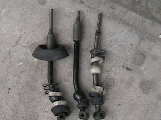 Three car shifter assemblies laid out on a concrete surface