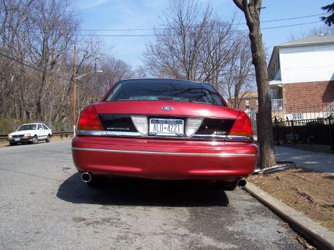 1999 Ford Crown Victoria - Rear view of a red 1999 Ford Crown Victoria parked on a residential street.