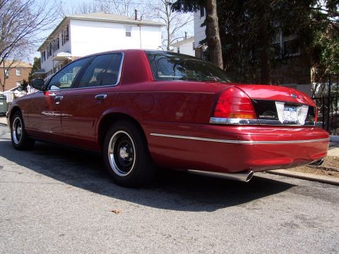 1999 Ford Crown Victoria - Rear view of a red Ford Crown Victoria sedan parked on a residential street.
