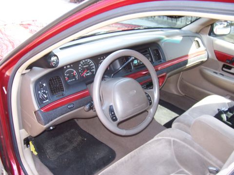 1999 Ford Crown Victoria - The dashboard of a 1999 Ford Crown Victoria features wood trim accents and an aftermarket gauge on the A-pillar.