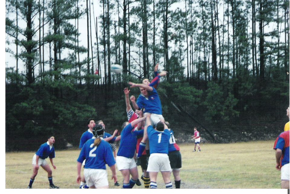 Rugby players in blue and red uniforms jumping for the ball during a game