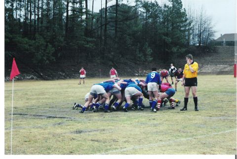 1992 Ford Bronco - Rugby match in progress with players engaged in a scrum and a referee observing the play.