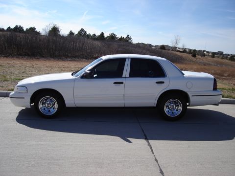 2000 Ford Crown Victoria - Side profile of a white 2000 Ford Crown Victoria sedan on a sunny day.