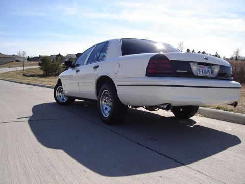 2000 Ford Crown Victoria - Rear view of a white 2000 Ford Crown Victoria, aftermarket chrome wheels and tinted taillights.