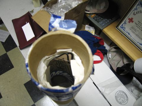 1991 Ford LTD Crown Victoria - open cardboard mailing tube and assorted packaging sit on a checkered floor beside a framed certificate and clutter.