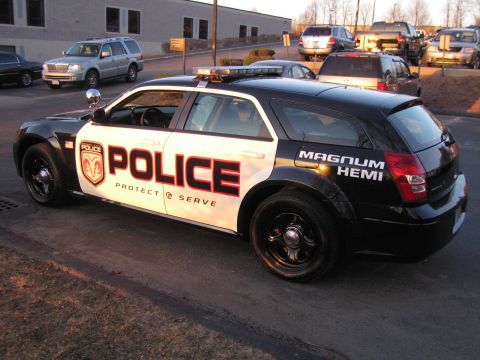 1991 Ford LTD Crown Victoria - Side profile of a black-and-white Dodge Magnum police wagon showing a ram-crest badge, POLICE text, and MAGNUM HEMI lettering.