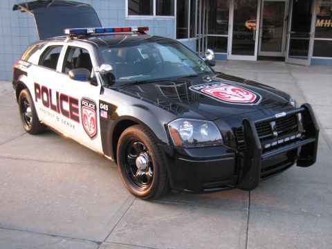 1991 Ford LTD Crown Victoria - black-and-white Dodge Magnum police wagon with raised hood, push bar, light bar, and a ram-crest decal on the hood.