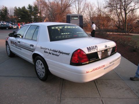 1991 Ford LTD Crown Victoria - Rear three-quarter view of a white Crown Victoria with M-H-Q Municipal Equipment sales lettering and website decals on the bumper.