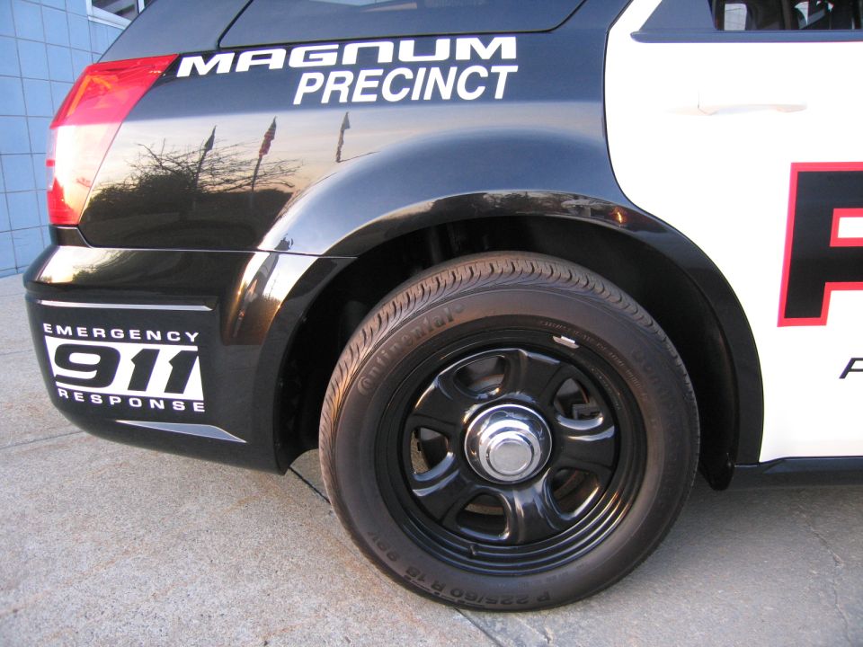 Rear quarter close-up of black police Magnum with 911 and PRECINCT decals
