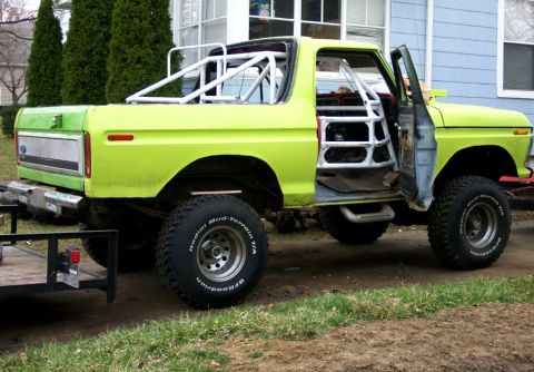 1978 Ford Bronco - This 1978 Ford Bronco features a prominent white rollcage and is viewed from the front three-quarter angle.