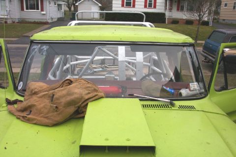 1978 Ford Bronco - Interior view of a heavily modified vehicle, a prominent roll cage and a jacket draped over the dashboard.