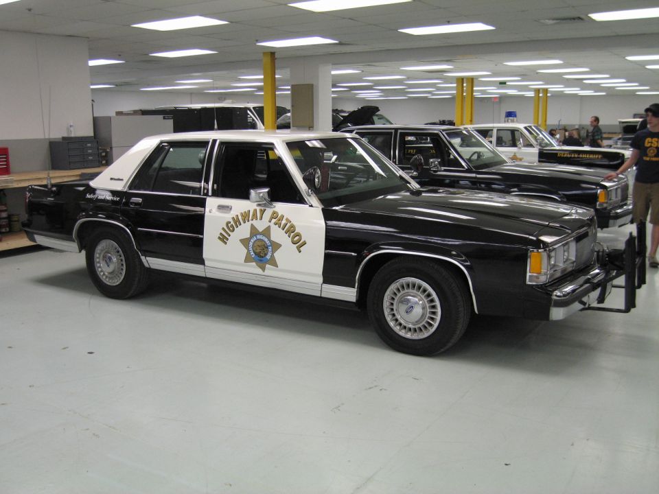 Black and white Highway Patrol Ford Crown Victoria sedan parked indoors