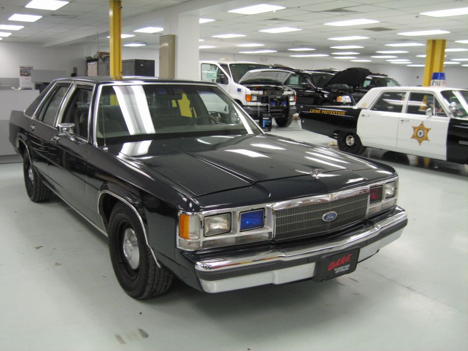 Dark Ford LTD Crown Victoria sedan with DARE decal and blue dash light indoors