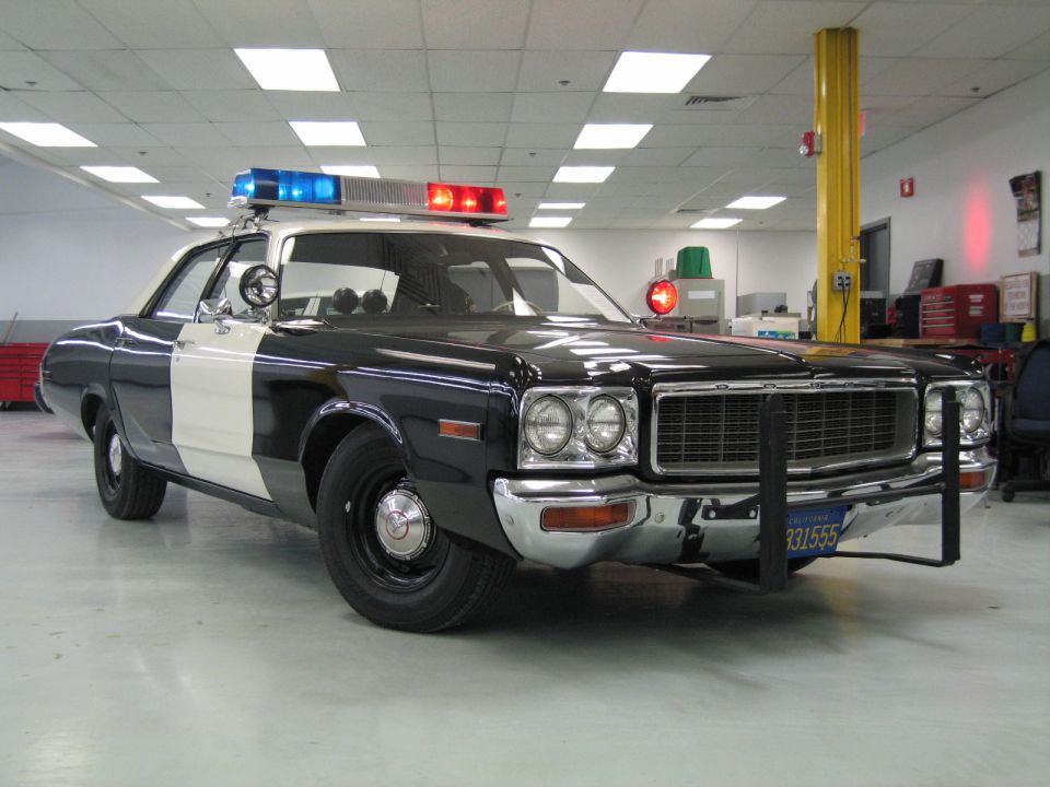 Black-and-white Dodge police cruiser, front three-quarter with DODGE grille badge