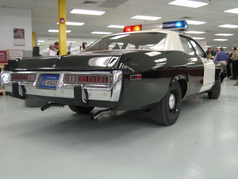 1991 Ford LTD Crown Victoria - Rear three-quarter view of a black-and-white police cruiser showing full-width segmented taillights, dual exhaust and California plate.