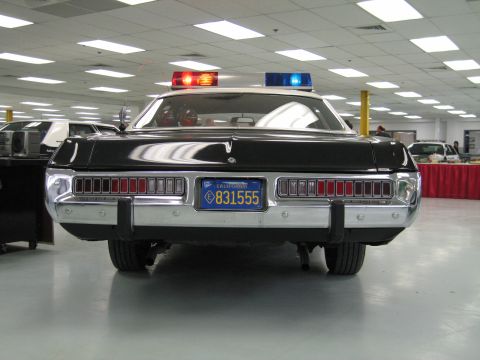 1991 Ford LTD Crown Victoria - Direct rear view of a black-and-white police cruiser with chrome bumper, full-width segmented taillights and blue California plate 831555.