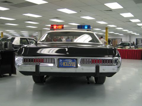 1991 Ford LTD Crown Victoria - Direct rear view of a black-and-white police cruiser showing full-width taillights, dual exhaust and a California license plate.