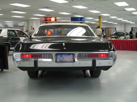 1991 Ford LTD Crown Victoria - Direct rear view of a black-and-white police cruiser with lit segmented taillights, chrome bumper and blue California plate 831555.