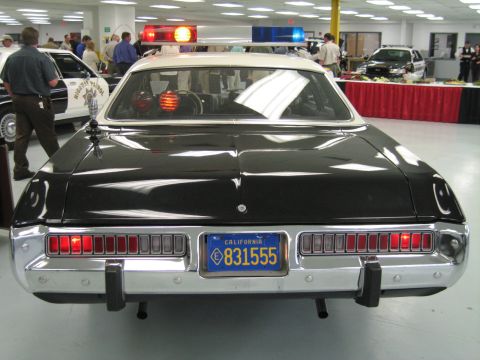 1991 Ford LTD Crown Victoria - Direct rear view of a black-and-white police cruiser with white vinyl roof, full-width taillights and blue California plate 831555.