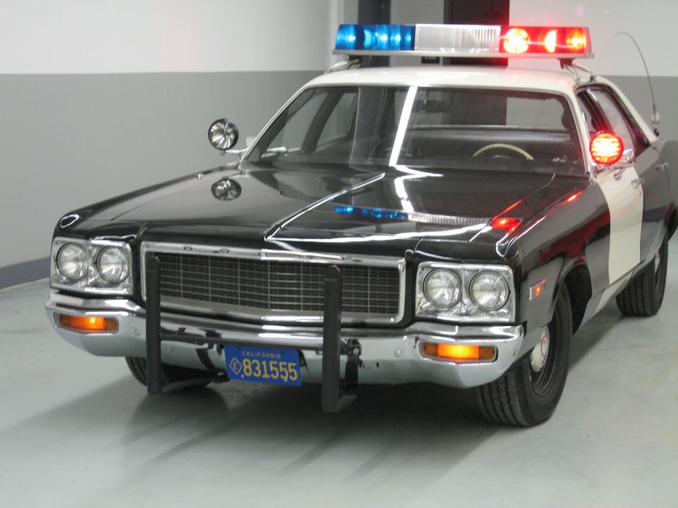 Front view of a black-and-white Dodge police car with chrome grille and push bumper