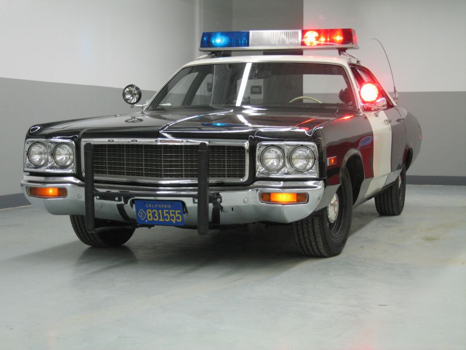 Black-and-burgundy Dodge police car with quad headlights and California plate 831555