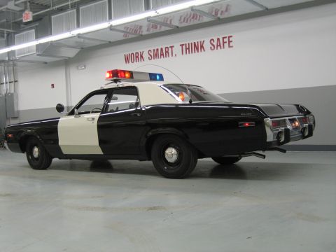 1991 Ford LTD Crown Victoria - black-and-white police sedan viewed from the rear quarter showing a POLICE badge on the rear fender in a garage.